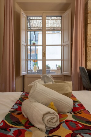 Une chambre d’hôtel avec un lit, une fenêtre avec des rideaux, un tapis coloré et une chaise.