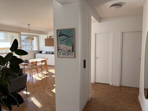 Ein modernes Interieur mit Essbereich, Küche und einem Flur, der zu einer Tür führt.