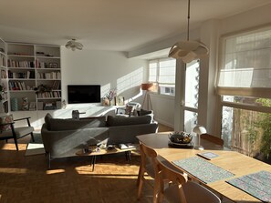 Ein modernes Wohnzimmer mit einer Couch, einem Esstisch und einem Bücherregal.