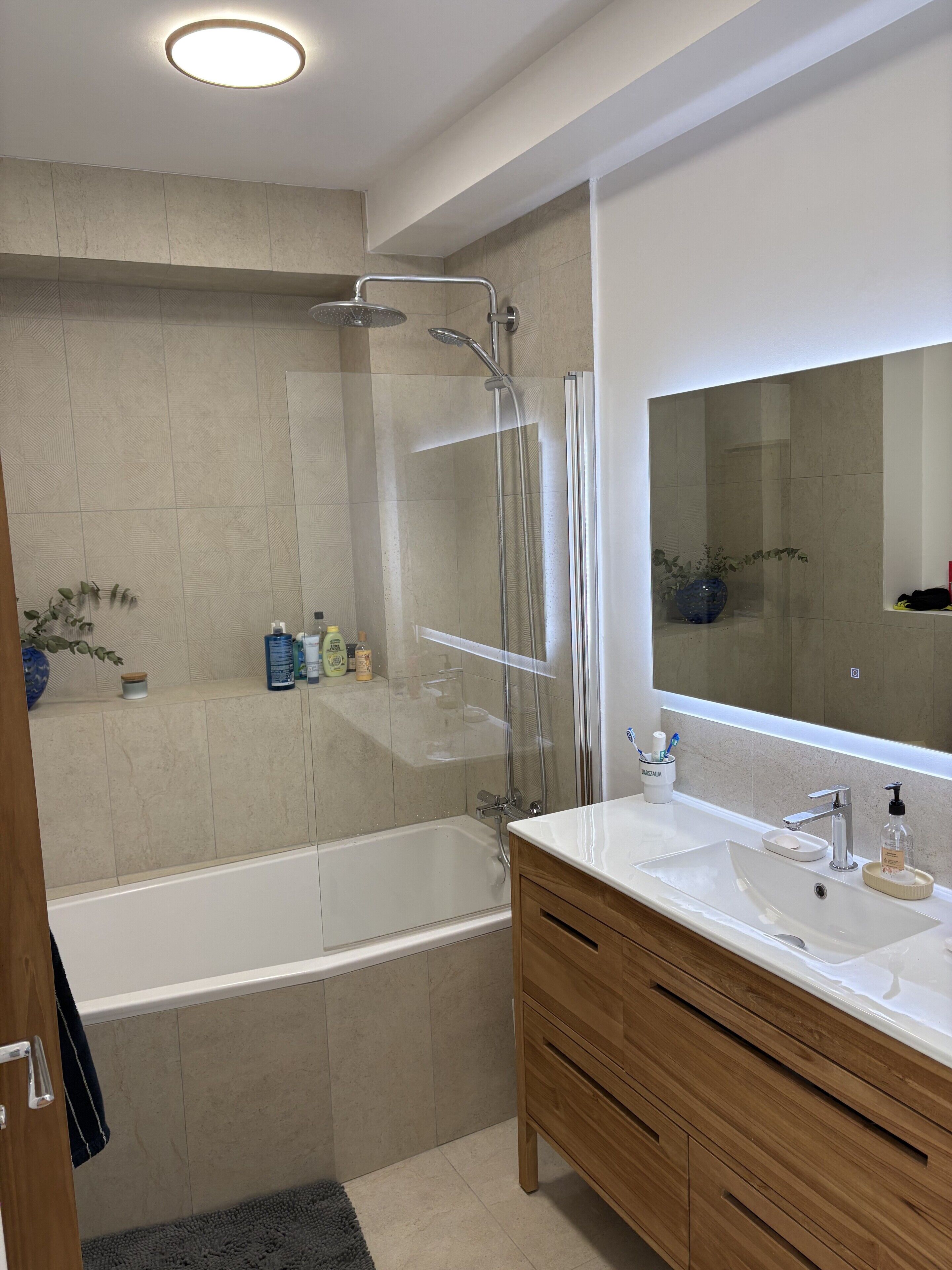 A modern bathroom with a glass-enclosed shower, a standalone bathtub, and a vanity with a mirror.