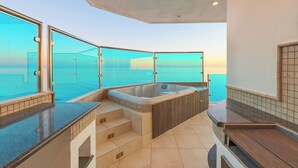 Een moderne badkamer met een ruime badkuip, een douche met glazen wand en uitzicht op de oceaan.