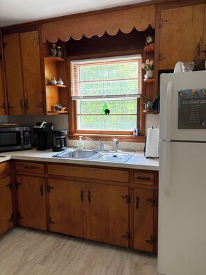 Eine Küche mit Holzausstattung, einem doppelten Spülbecken, einer Mikrowelle, einer Kaffeemaschine und einem Kühlschrank.