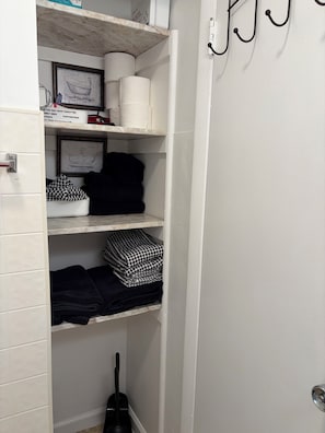 Ein helles Badezimmer mit Toilettenpapierhalter, einem gerahmten Bild und einem schwarz-weiß karierten Handtuch.