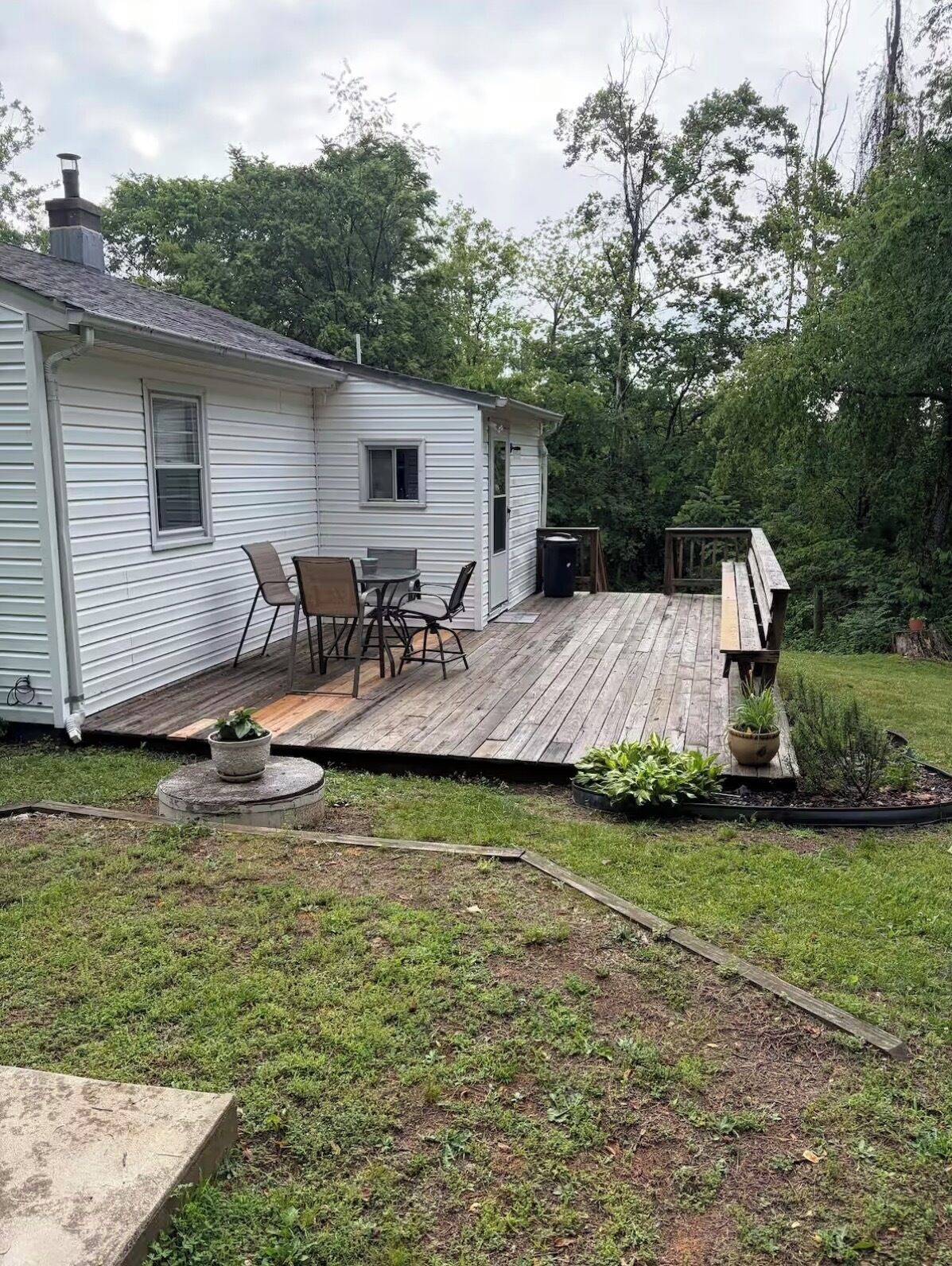 Une maison de plain-pied dotée d’une terrasse, d’un petit espace salon extérieur et d’un jardin.