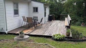 Une maison de plain-pied dotée d’une terrasse, d’un petit espace salon extérieur et d’un jardin.