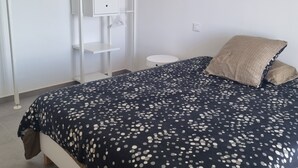 Un dormitorio con cama, armario, lámpara colgante y mesita de noche.