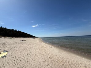 A beach with a sandy shore, a clear sky, and a calm sea.
