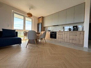Eine moderne Küche mit Holzausstattung, ein Essbereich mit Tisch und Stühlen sowie eine Sitzecke mit Sofa.