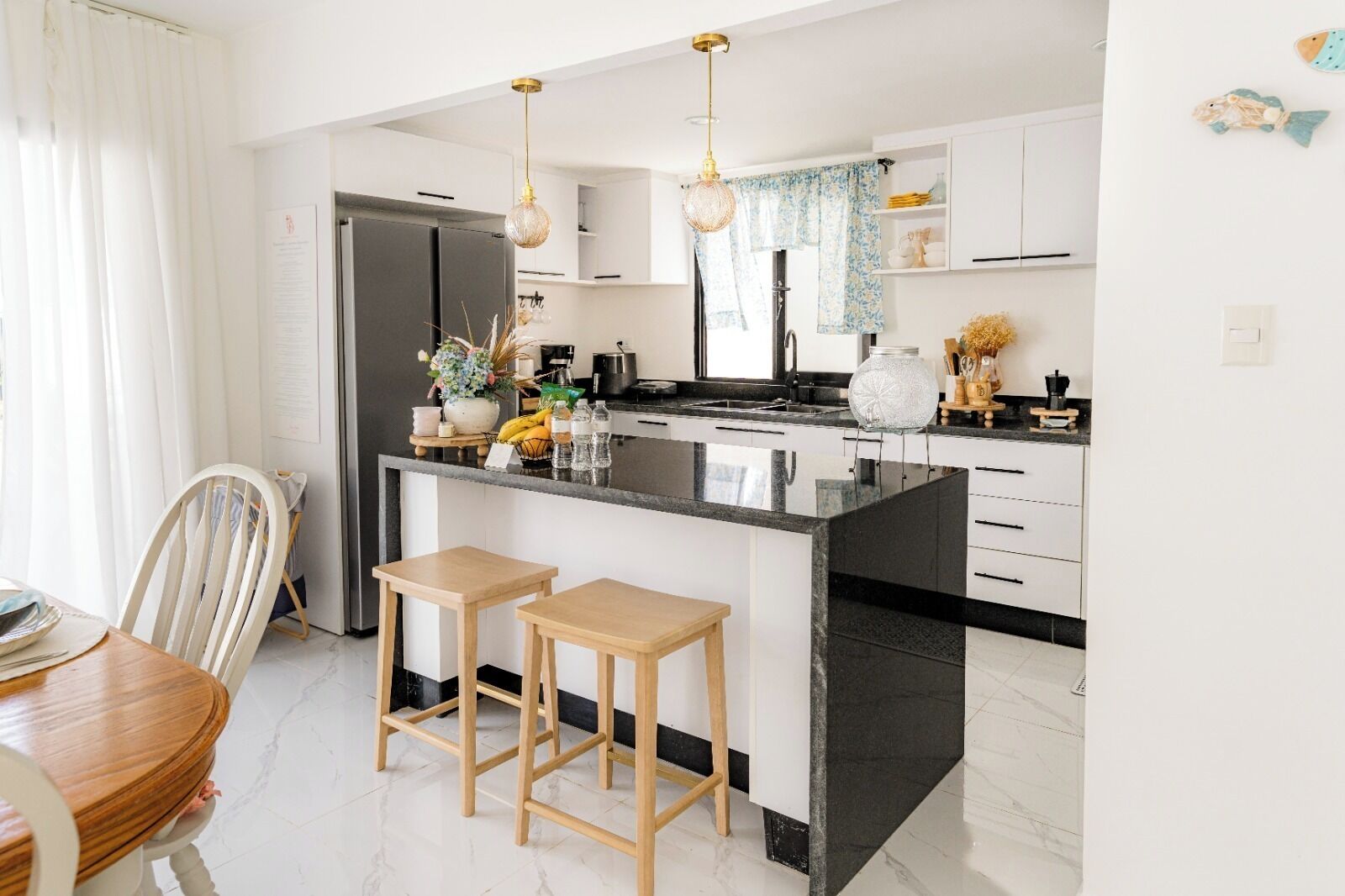 A modern kitchen with a black countertop, white cabinets, and two wooden stools.