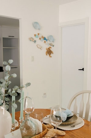 A dining area with a wooden table set for two, a white door, and wall decorations including fish and a turtle. - Villa for 7 people with private Picuzzi in Punta Cana. Close to everything! (Punta Cana)