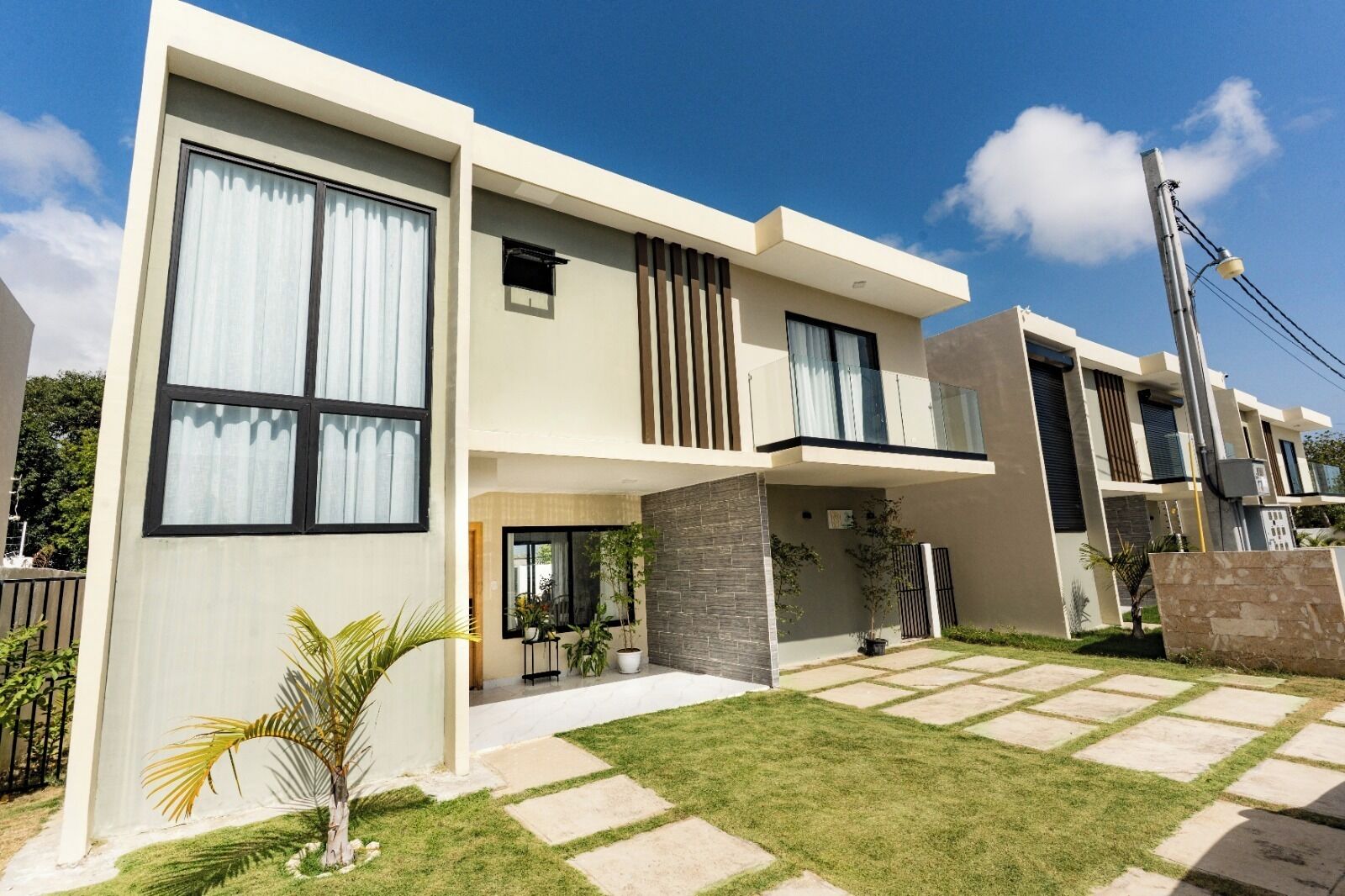 A modern two-story house with a flat roof, large windows, and a well-maintained lawn.