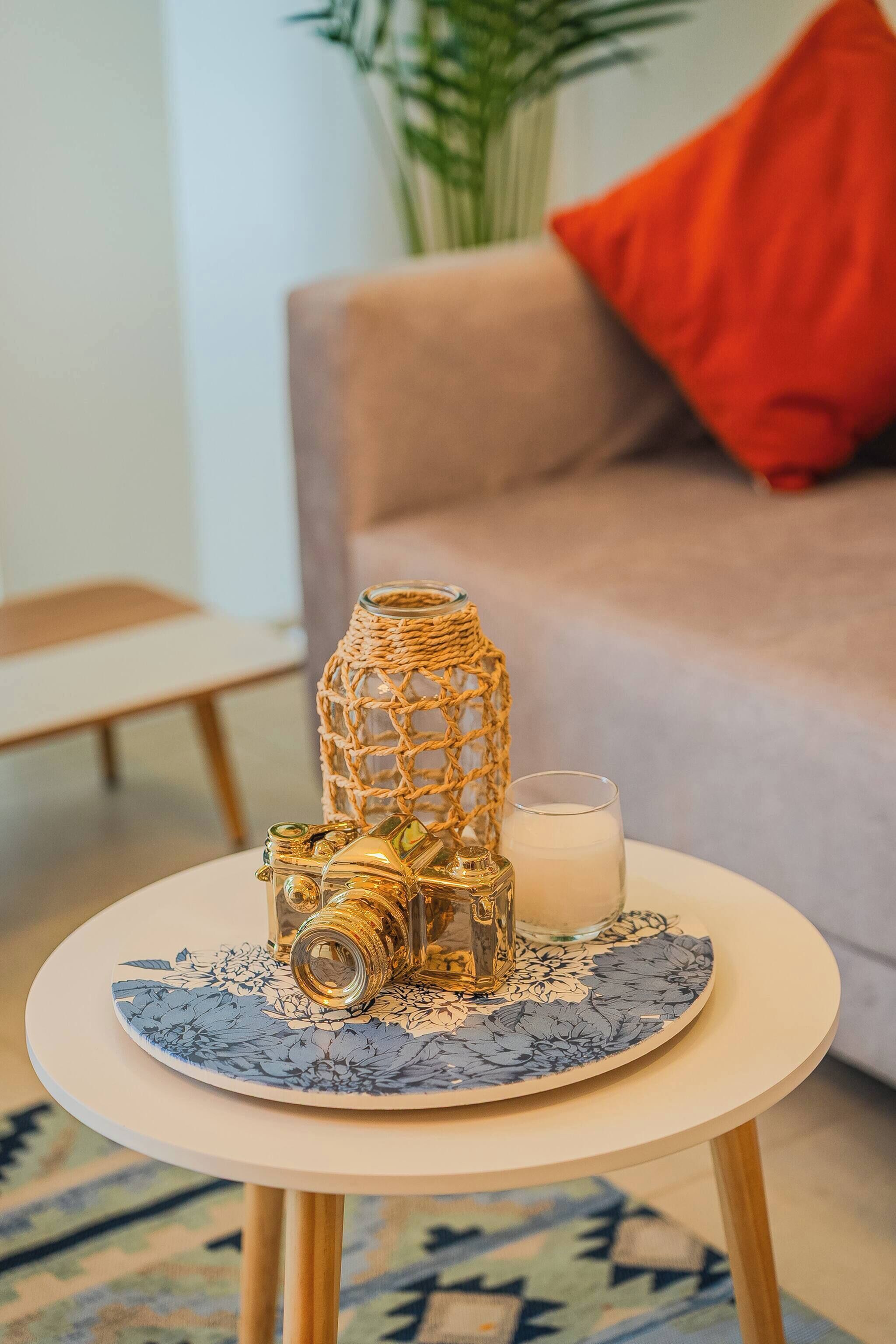 A round table with a decorative glass vase, a candle, and a glass of milk.