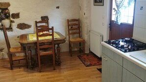 Een keuken met een eettafel, stoelen, een fornuis en een raam met gordijnen.