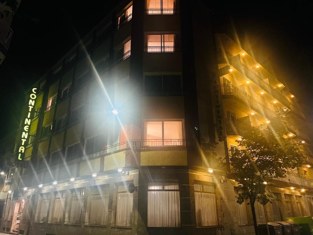 Un edificio de varios pisos con balcones y ventanas, iluminado con luz artificial.