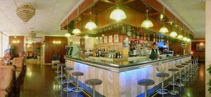 A bar area with a bartender, bar stools, and a counter with various bottles.