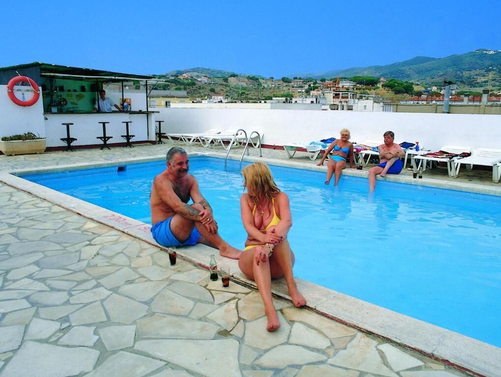 A swimming pool with stone tiles, a bar area, and a view of the hills.