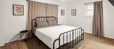 Un dormitorio con cama, ventilador de techo, ventana con cortinas y decoración en la pared.