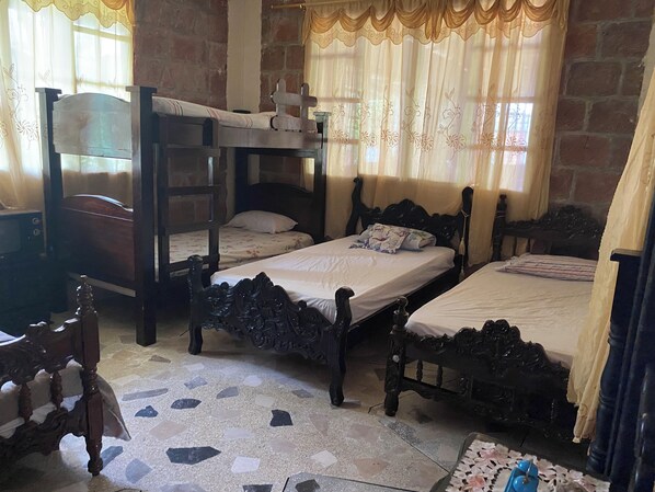A room with three wooden bunk beds, a wooden chair, and a small table with a tray of chocolates.