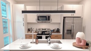 A modern kitchen with white cabinets, stainless steel appliances, and a central island with seating. - Dallas Downtown, FIFA Close to All the FUN! (Dallas)