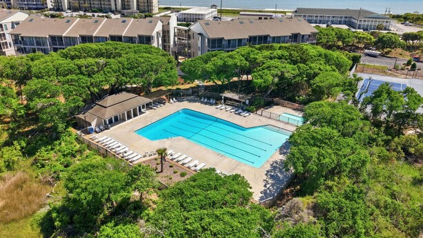 Piscina cercada por árvores, com edifícios ao fundo.