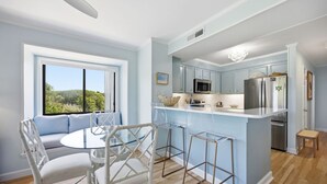 Cozinha moderna com área de bar, mesa de jantar com cadeiras e vista para o exterior.