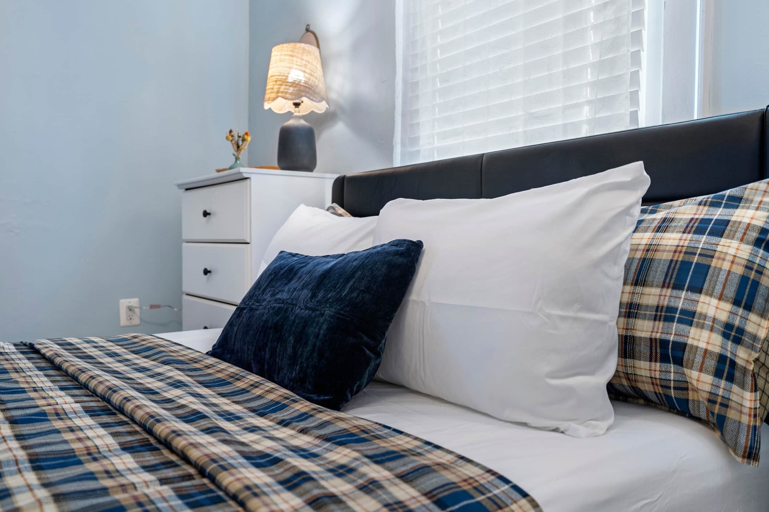 A bed with a plaid bedspread, white pillows, and a dark headboard.