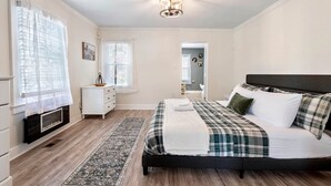 A bedroom with a bed, a dresser, a nightstand, a fireplace, and a hallway. - The Retreat at Harpers Ferry (Bolivar)
