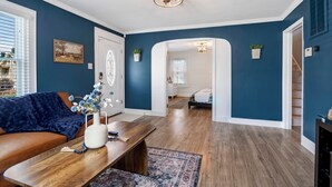 A living room with a dark blue wall, a wooden coffee table, a blue sofa, and a chandelier. - The Retreat at Harpers Ferry (Bolivar)