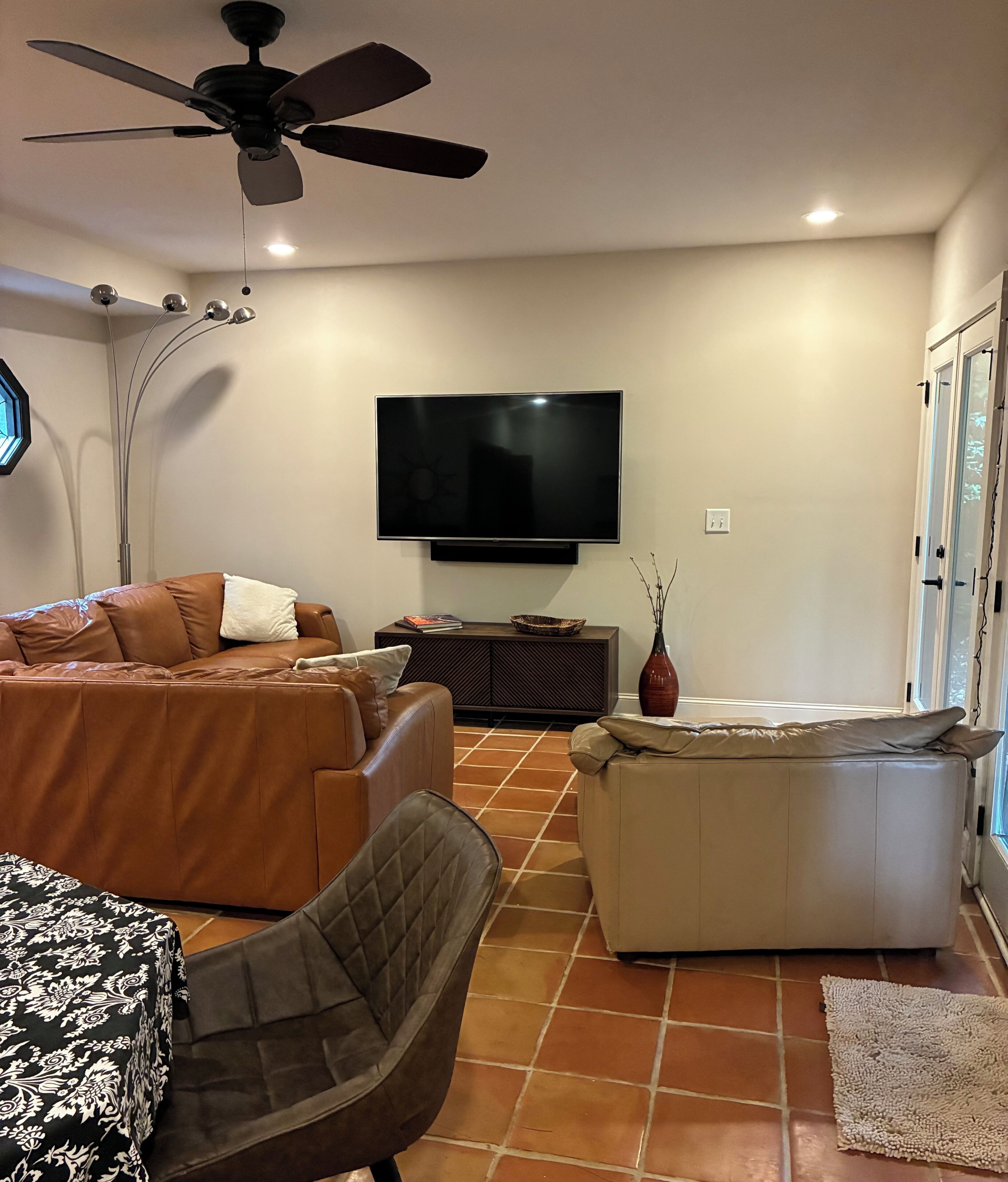 A living room with a TV, a ceiling fan, a sofa, a chair, and a coffee table.