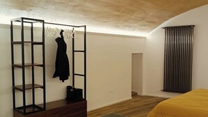 Een slaapkamer met een bed, een houten vloer, een radiator en een kapstok met kleding.