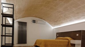 Een kamer met een bed, een radiator, een airconditioning en een houten vloer.