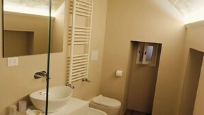 Een kleine, compacte badkamer met een witte wastafel, toilet en handdoekrek.