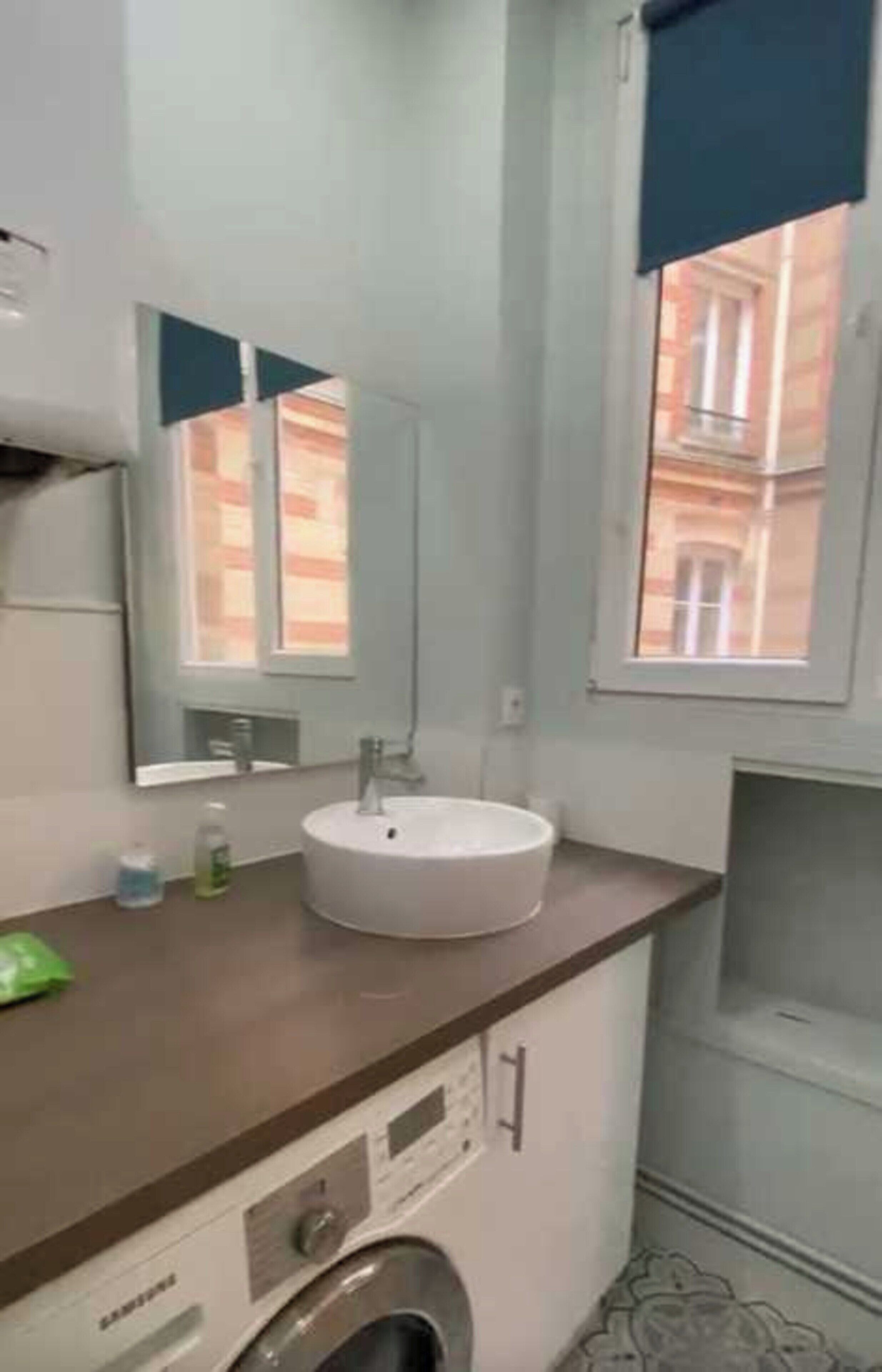 A bathroom with a sink, mirror, window, and a washing machine.