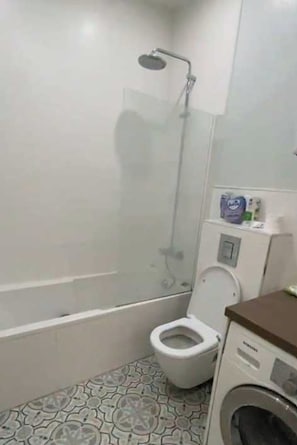 Appartement | Badkamer | Een bad, een haardroger, handdoeken, shampoo