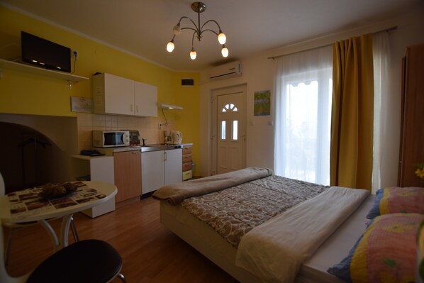 A compact hotel room with a bed, a small kitchenette, a dining table, and a chair. - Studio Apartment With Terrace and sea View (Opatija)