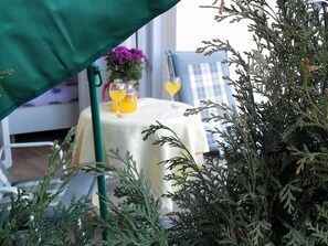 A table with a white tablecloth, two glasses of orange juice, and a vase with purple flowers. - Studio Apartment With Terrace and sea View (Opatija)