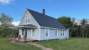 A single-story house with a dark roof, a front porch with steps, and a brick chimney. - Cozy 2 bedroom house near New River, game room, WiFi, brand new kitchen/bathroom (Galax)