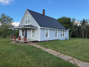 A single-story house with a dark roof, a front porch with steps, and a brick chimney. - Cozy 2 bedroom house near New River, game room, WiFi, brand new kitchen/bathroom (Galax)