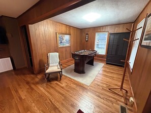 A room with wooden walls, a foosball table, a chair, and a painting on the wall. - Cozy 2 bedroom house near New River, game room, WiFi, brand new kitchen/bathroom (Galax)
