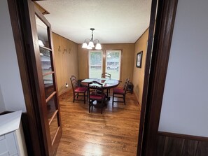 A dining area with a wooden table, chairs, and a chandelier. - Cozy 2 bedroom house near New River, game room, WiFi, brand new kitchen/bathroom (Galax)