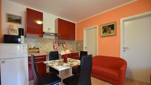 Una cocina compacta con mesa, sillas, refrigerador y un sofá rojo.