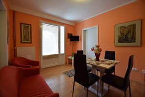 A living room with a sofa, dining table, chairs, a TV, and artwork on the walls. - Spacious Apartment With Terrace and Outdoor Kitchen With sea View (Opatija)