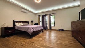 A bedroom with a bed, nightstand, dresser, and a ceiling light fixture.