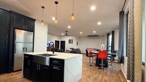 A modern kitchen with a central island, black cabinets, and a stainless steel refrigerator.