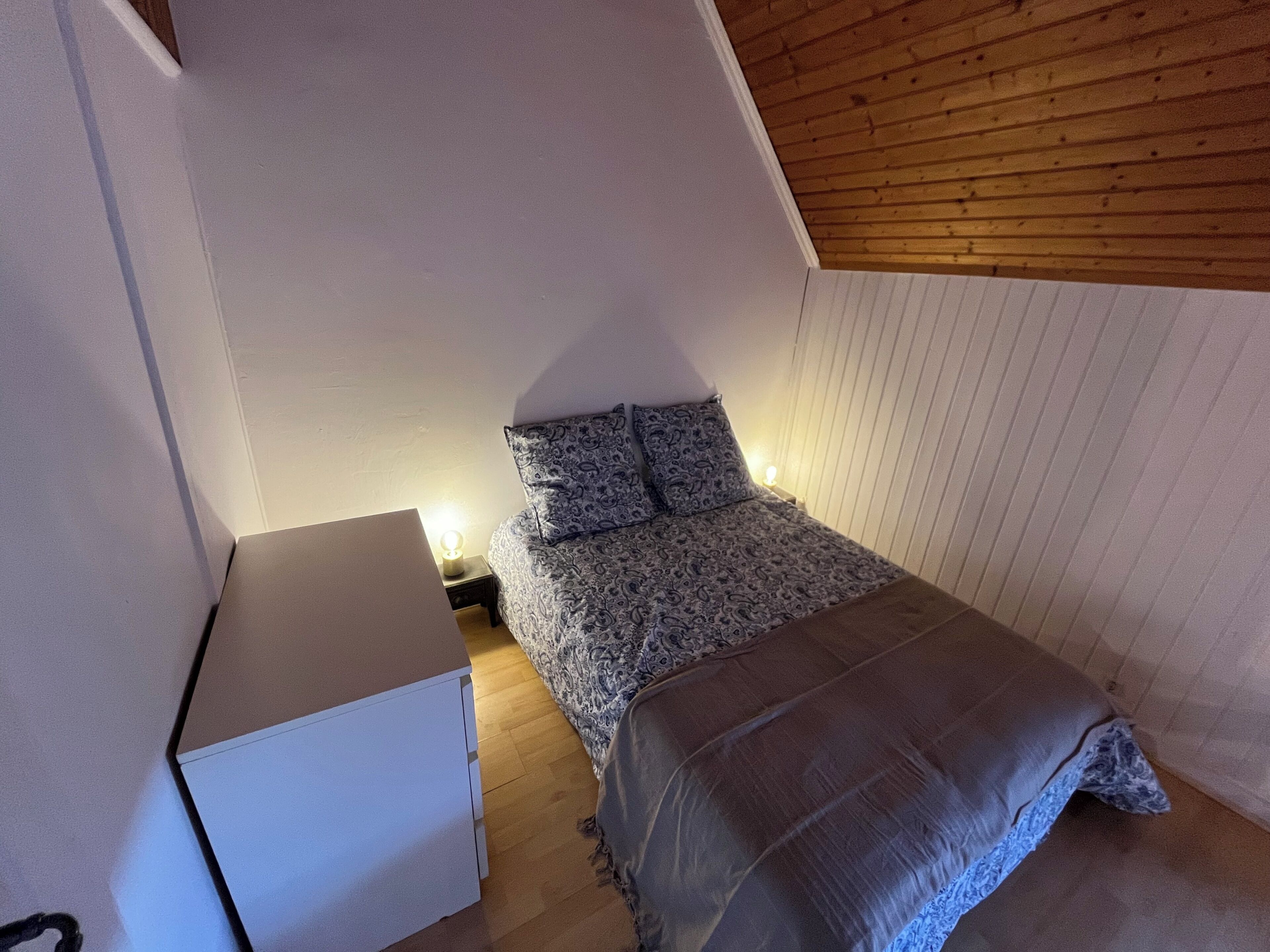 A bedroom with a bed, bedside table, and a dresser.