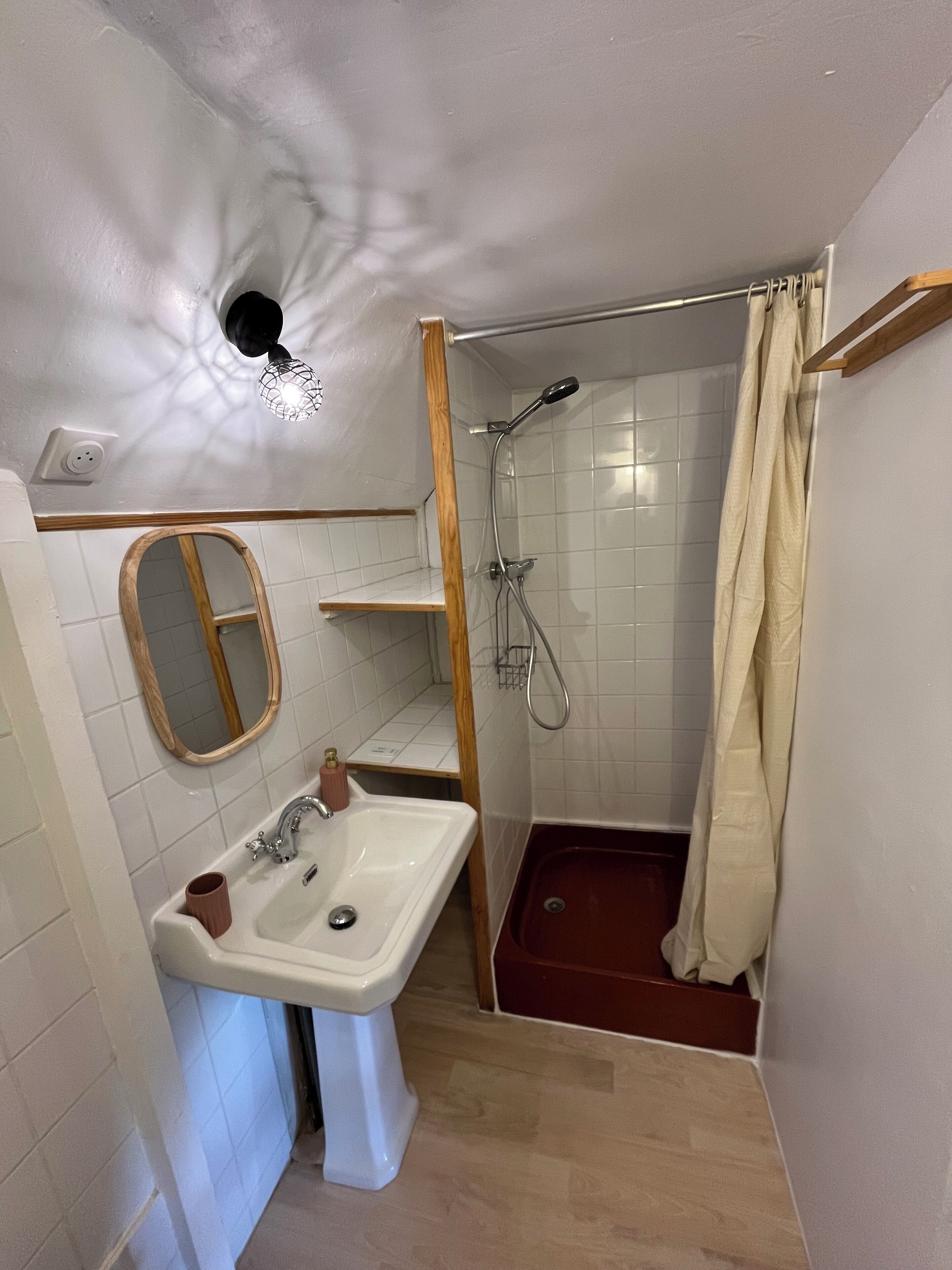 Une salle de bain équipée d’un lavabo, d’un miroir, d’une douche et d’un porte-serviettes.