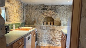 A kitchen with stone walls, a built-in oven, and wooden cabinets. - La Petite Maison (Peyzac-le-Moustier)
