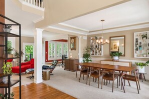 Un vaste salon comprenant un coin repas, un plancher en bois et un escalier menant à l’étage supérieur.