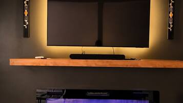 A flat-screen TV mounted on a wall above a wooden shelf, with a fireplace below.