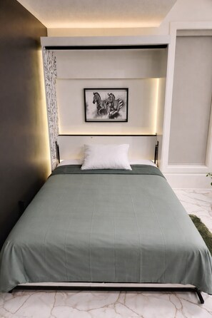Quarto moderno com colcha verde, uma obra de arte com tema de zebra emoldurada acima da cama e piso de mármore.